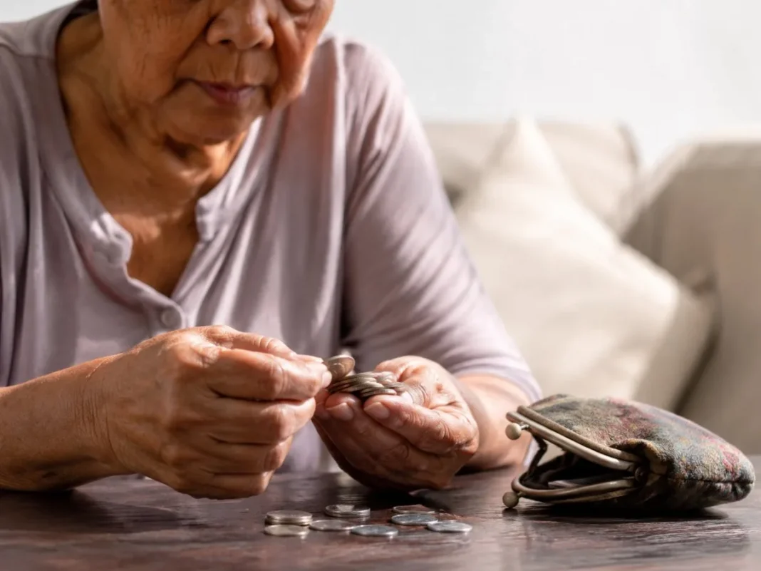 Persona mayor contando monedas sobre una mesa